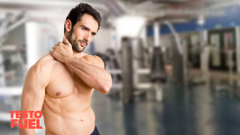 Athletic man holds his neck whilst in the gym in pain