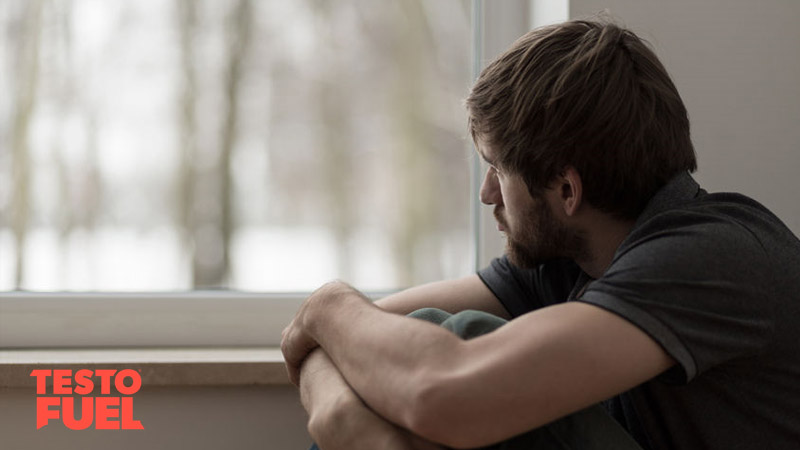 Young man suffering from anxiety sat looking out of a window