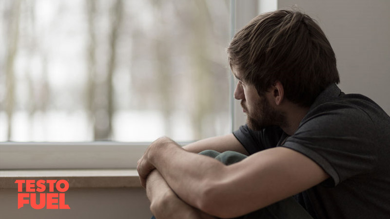 Young man suffering from anxiety sat looking out of a window