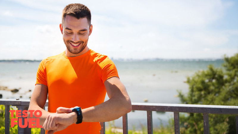 Athletic young runner wearing a heart rate monitor smiling on the beach