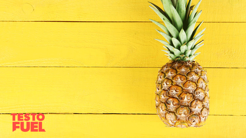 A pineapple laid on a bright yellow wooden table