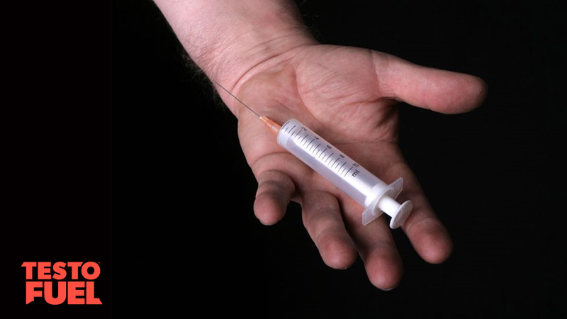 A bodybuilder holding a needle in the palm of his hand on black background