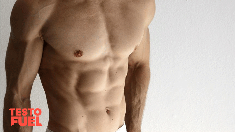 Muscular shirtless man shows off toned abs and chest on white background