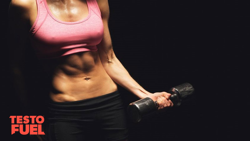 Woman in pink sports top lifting a weight as a bicep curl on black background