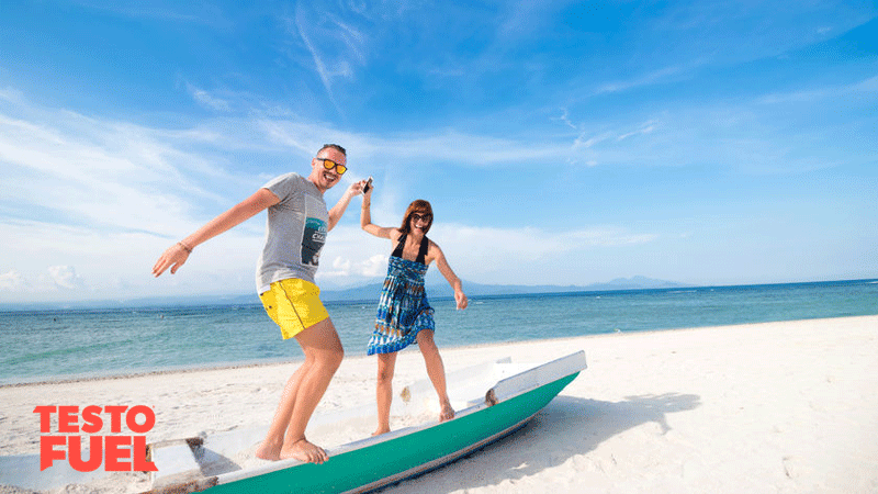 Happy young joyful couple having beach fun laughing together during summer holidays vacation on tropical beach with white sand. Beautiful energetic fresh, man and woman.