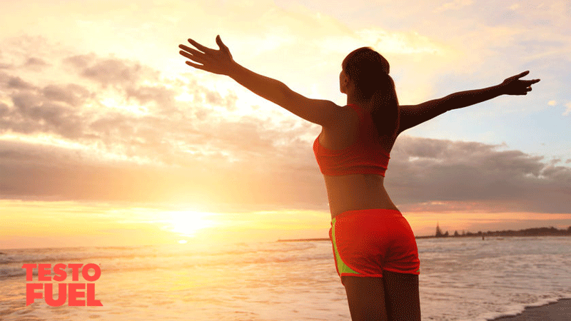Woman in sportswear enjoying the sunrise on the beach