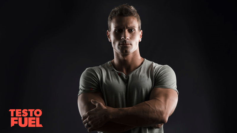 Muscular bodybuilder posing with arms folded on black background